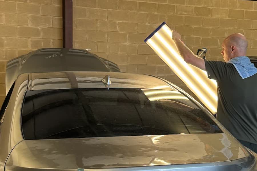 An assessor holds a light board over a car to read the panel